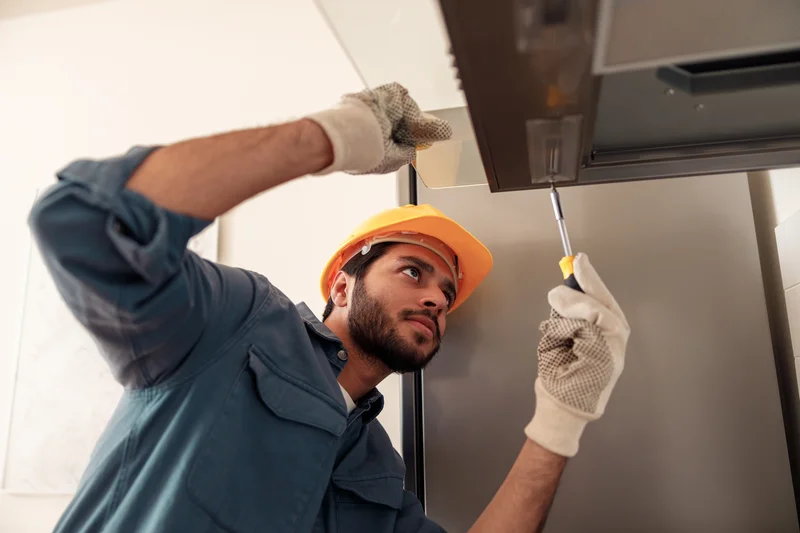 Remodeling contractor in hard hat installing range hood ventilation in kitchen Remodeling contractor in hard hat installing range hood ventilation in kitchen