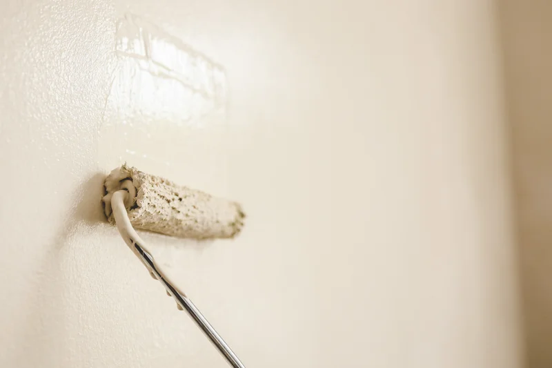 Paint roller applying light beige paint to an interior wall. Paint roller applying light beige paint to an interior wall.