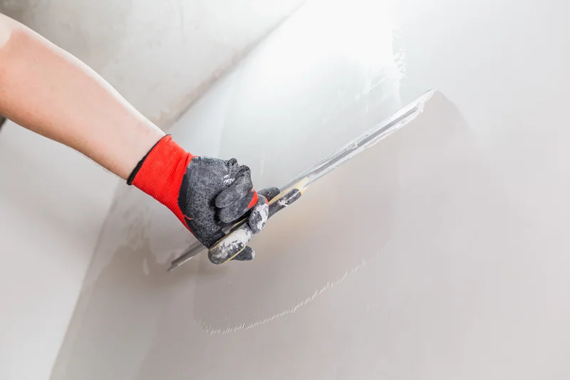Plasterer smoothing plaster on a wall using a metal trowel