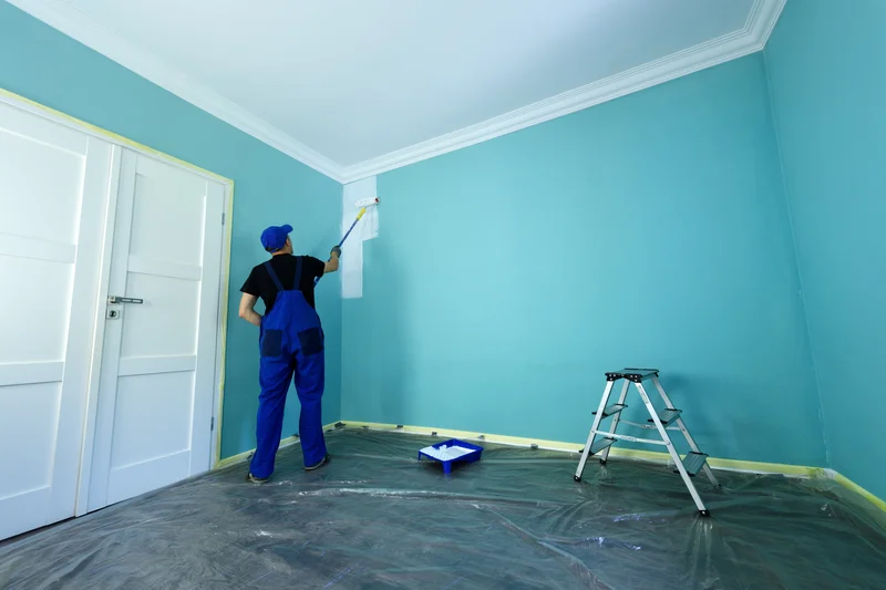 Professional painter using roller to paint a bright turquoise room